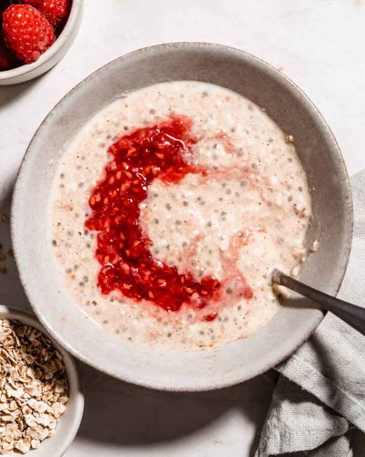 Brids-eye view of overnight oats for baby in a bowl topped with mashed raspberries.