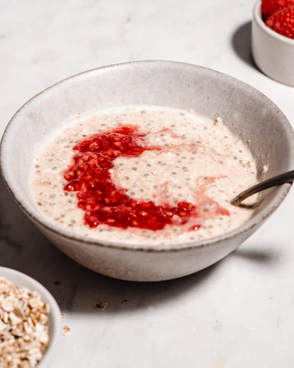 Overnight oats for baby in a bowl topped with mashed raspberries.
