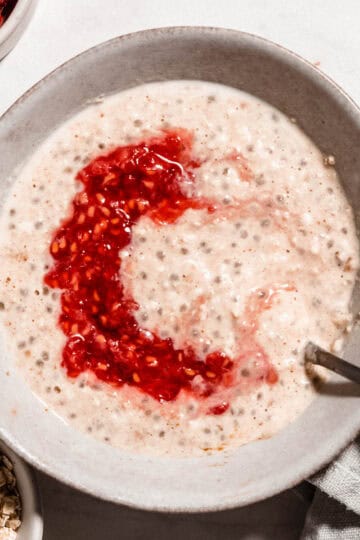 Brids-eye view of overnight oats for baby in a bowl topped with mashed raspberries.