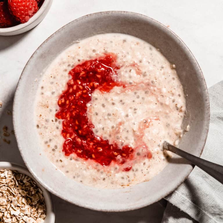 Brids-eye view of overnight oats for baby in a bowl topped with mashed raspberries.