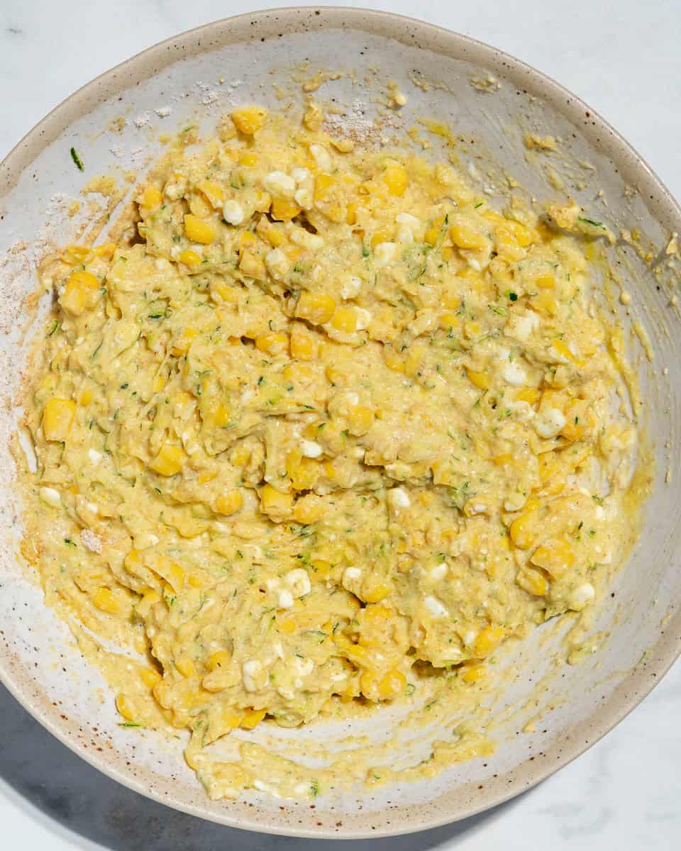 All ingredients for sweetcorn fritters whisked together in a soup plate.