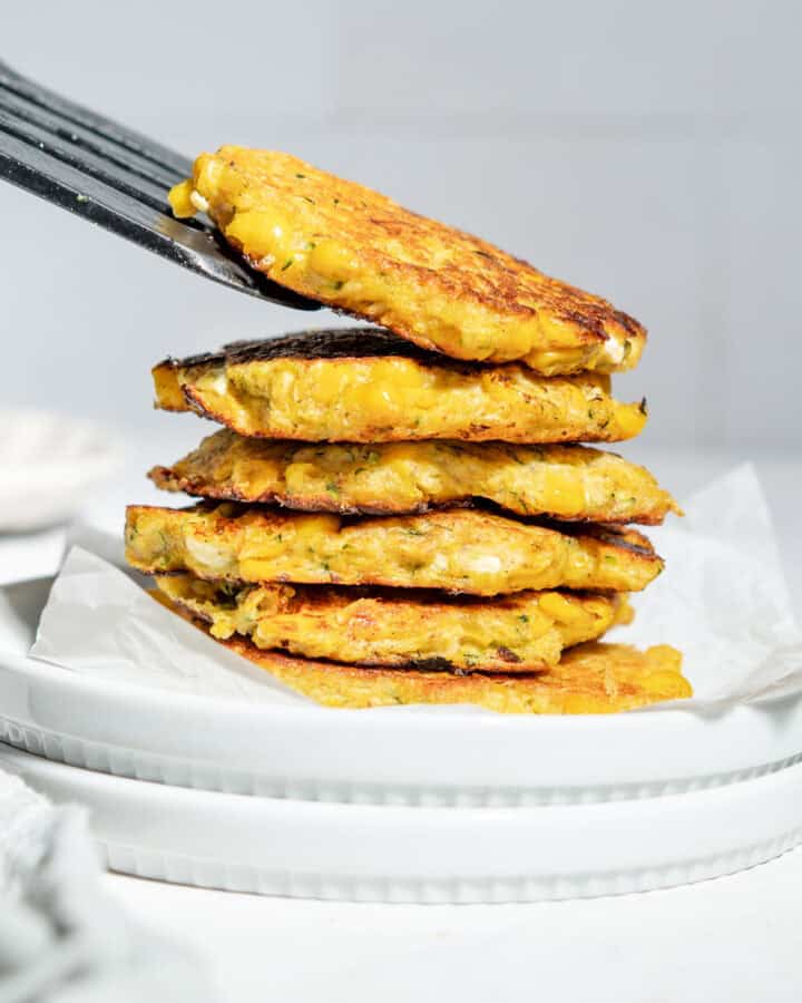 A stack of sweetcorn fritters on a plate.