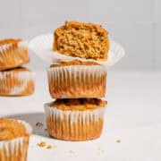 A stack of 3 carrot banana zucchini muffins with the upper one showing the texture inside.