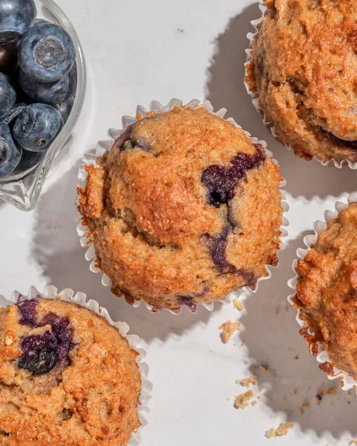 Birds-eye view of 4 blueberry lemon cottage cheese muffins. Next to it some blueberries.