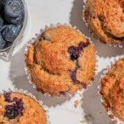 Birds-eye view of 4 blueberry lemon cottage cheese muffins. Next to it some blueberries.