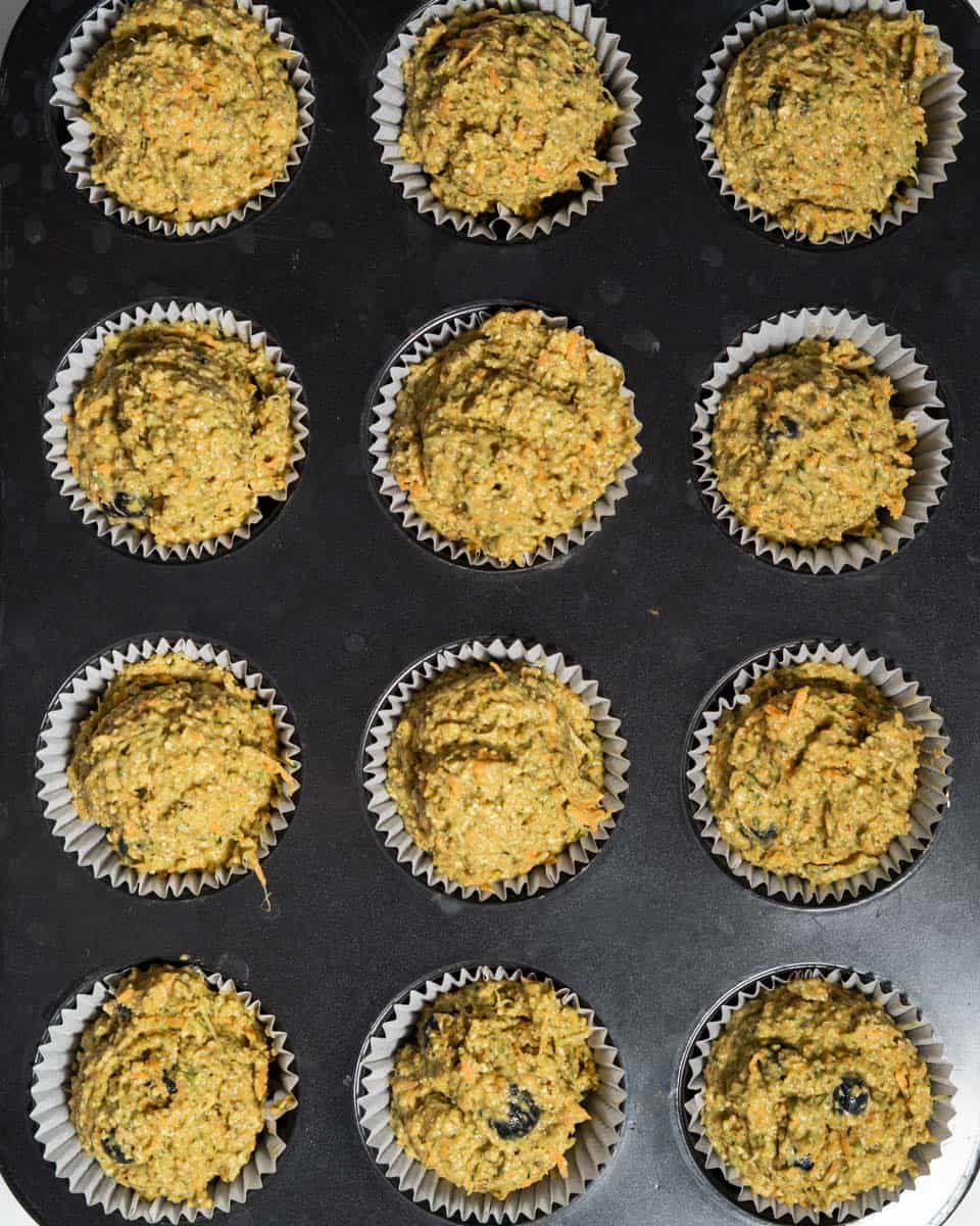 Muffin batter spooned into muffin tins.