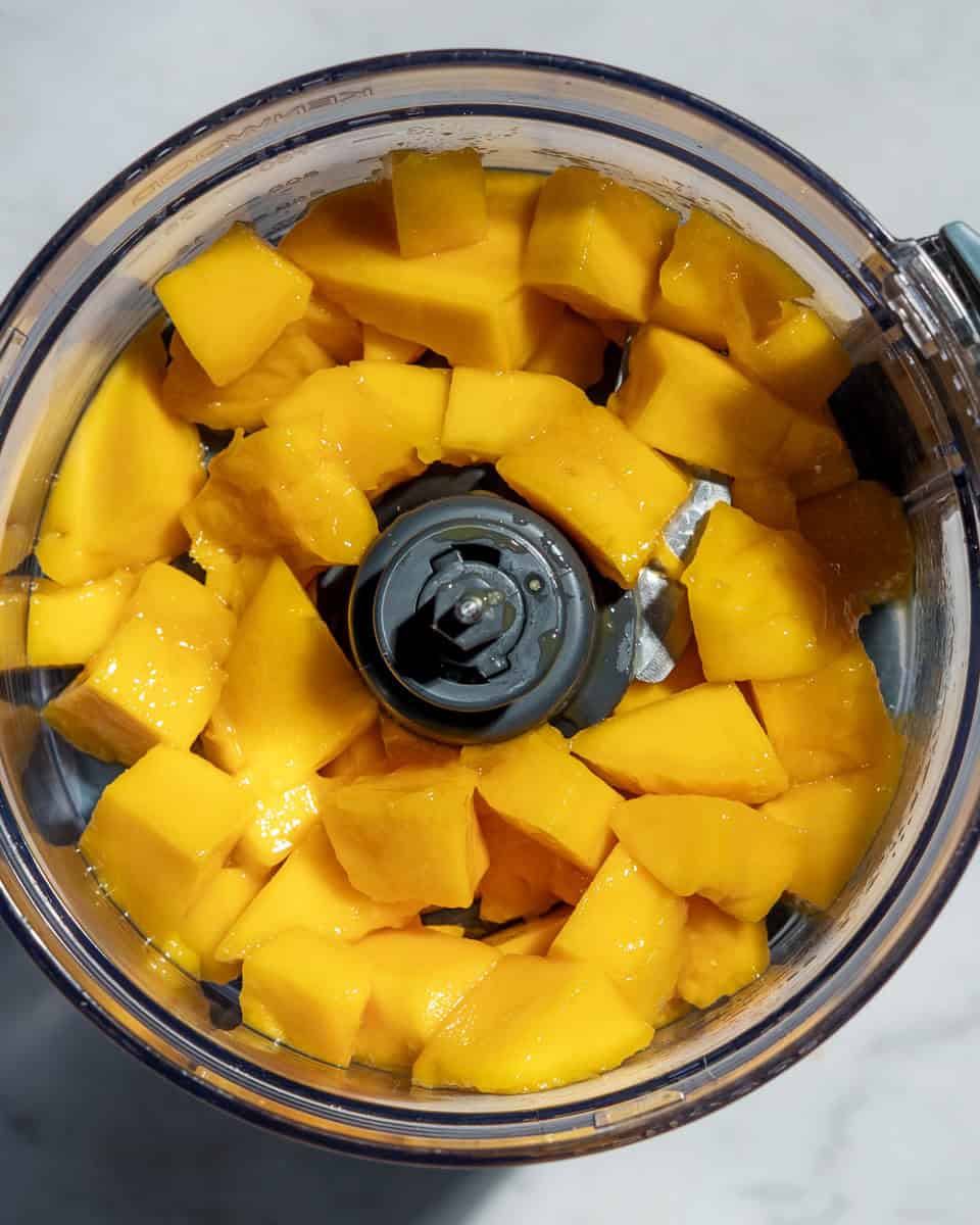 Mango pieces in a food processor.