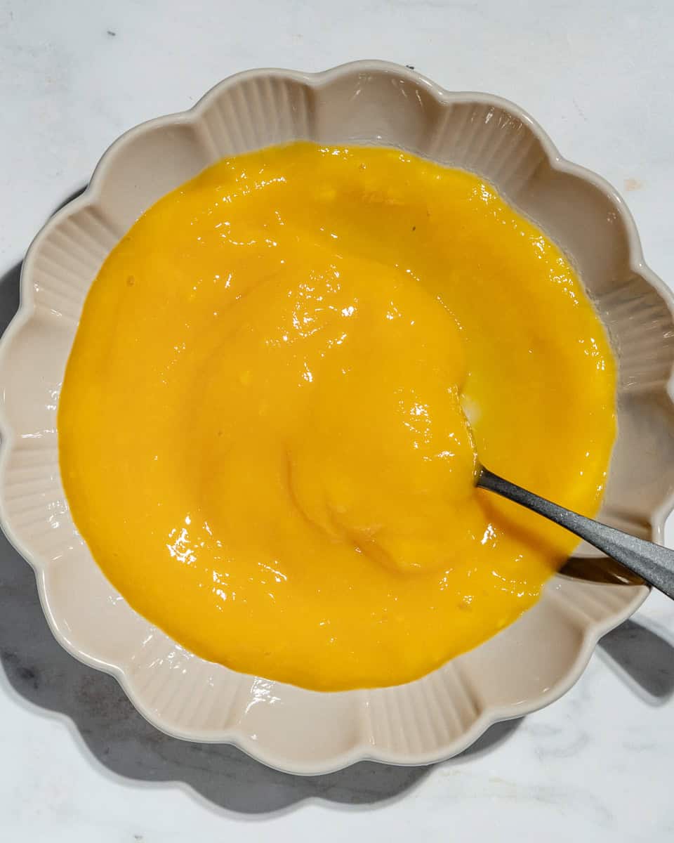 Mango puree on a plate with a spoon in.