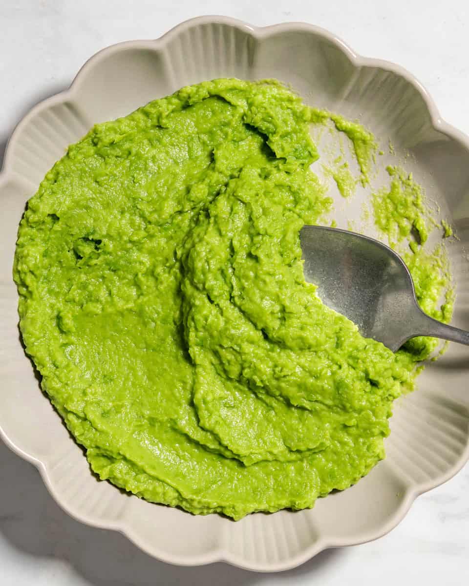 Pea puree in a plate with a spoon in.