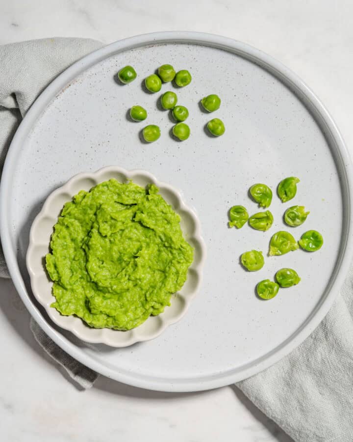 Pea puree, mashed peas and whole cooked peas on a plate.