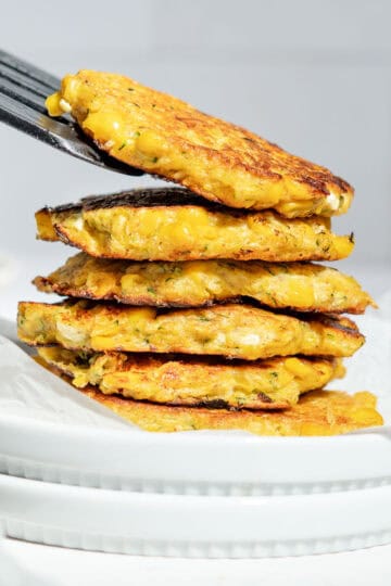 A stack of sweetcorn fritters on a plate.
