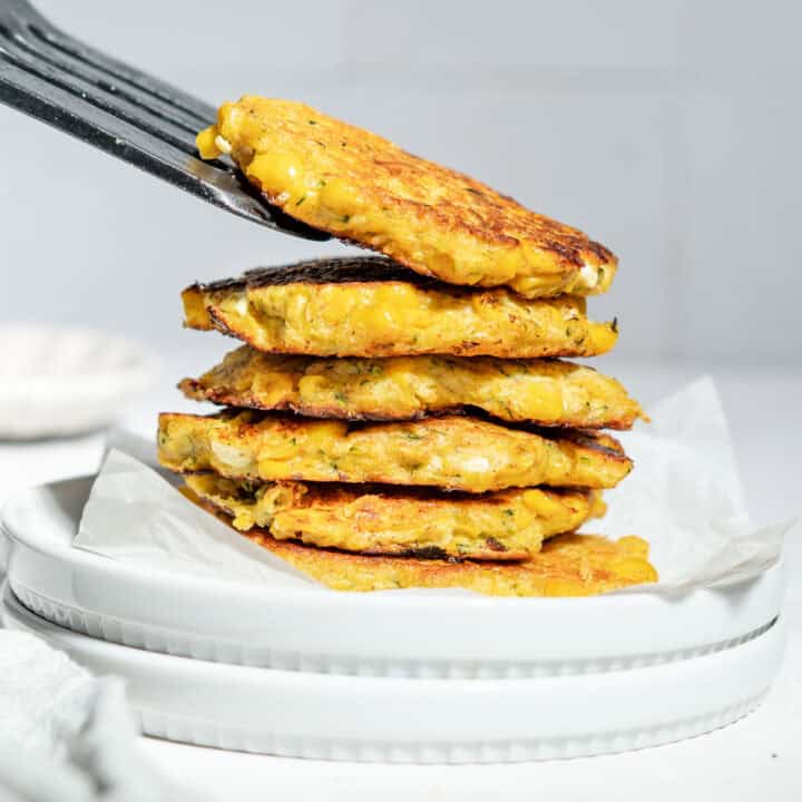 A stack of sweetcorn fritters on a plate.