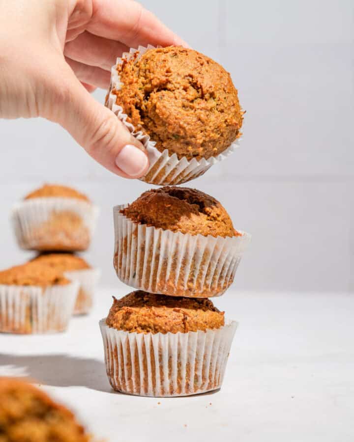 Stack of 3 zucchini sweet potato muffins with the upper one being taken away.