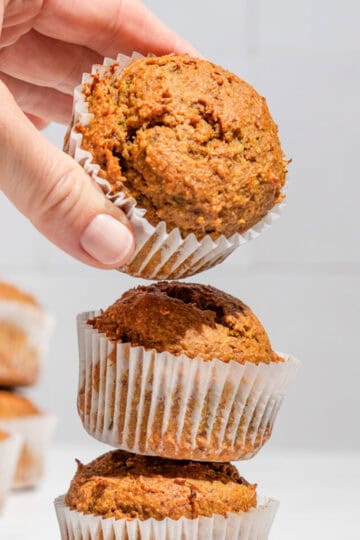 Stack of 3 zucchini sweet potato muffins with the upper one being taken away.