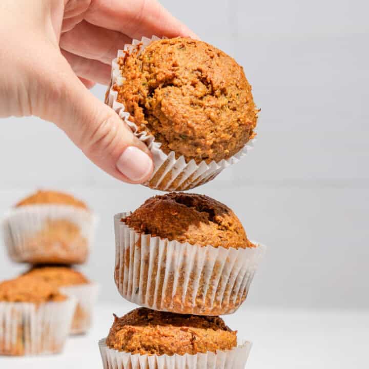 Stack of 3 zucchini sweet potato muffins with the upper one being taken away.