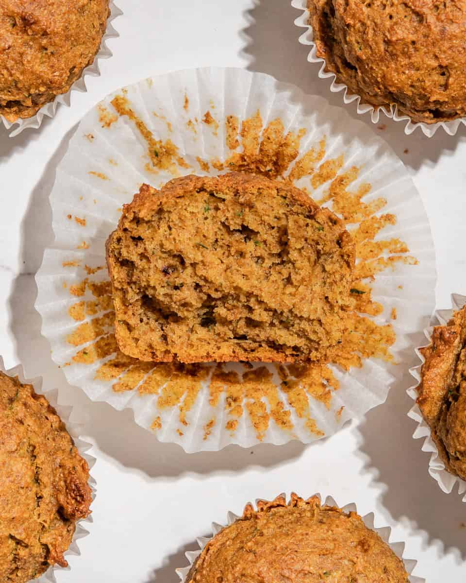 Birds-eye-view of a sweet potato zucchini muffin with a bite bitten off so you can see the texture inside.