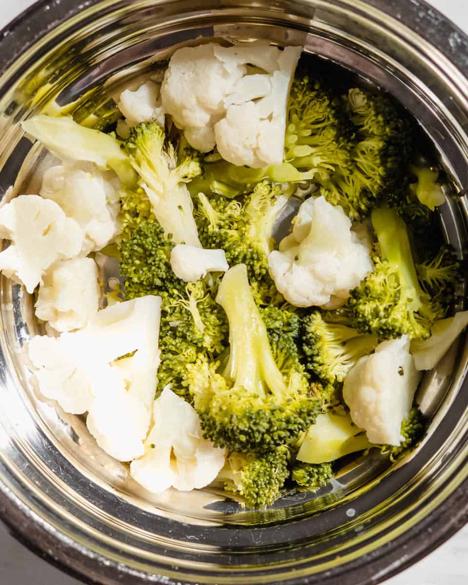 Steamed broccoli and cauliflower in a steamer basket.